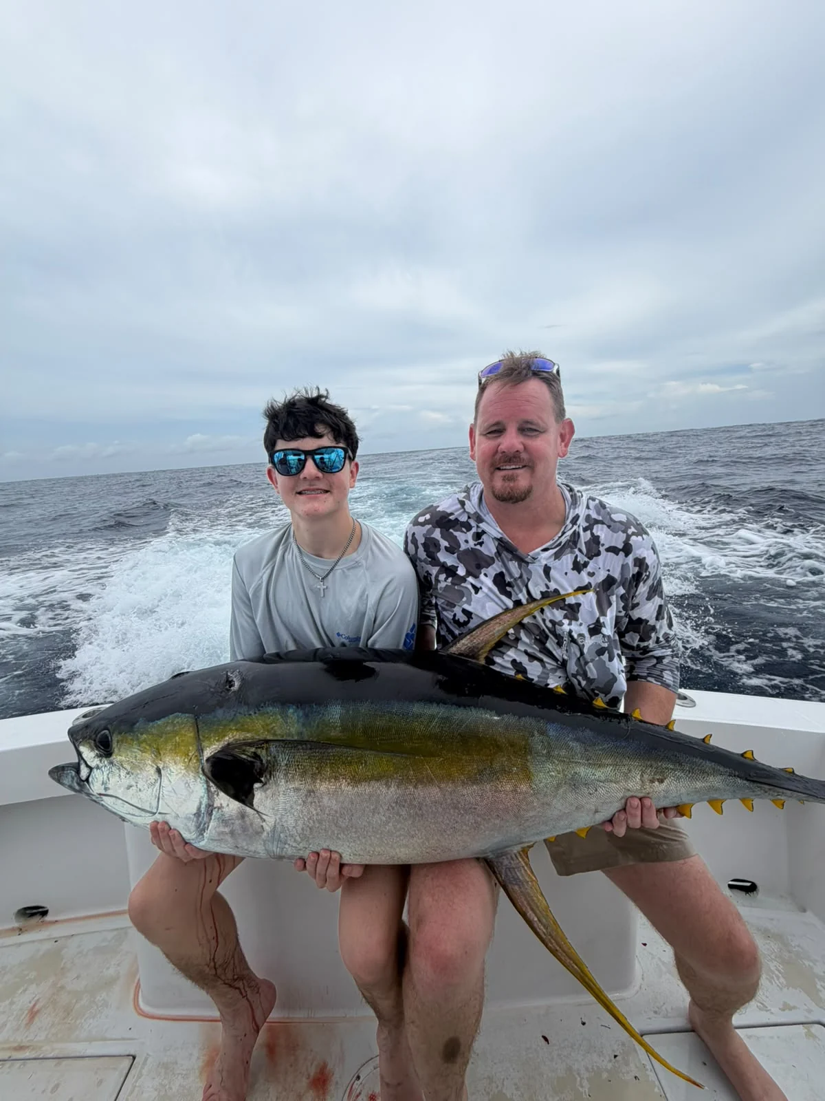 Family anglers holding a yellowfin tuna during a private offshore fishing charter from Jaco Costa Rica