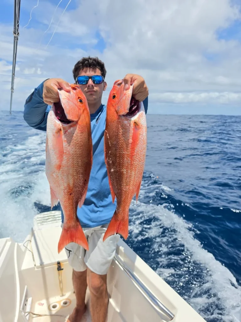 Angler holding two red snapper caught near Jaco Costa Rica during an August 2026 fishing charter
