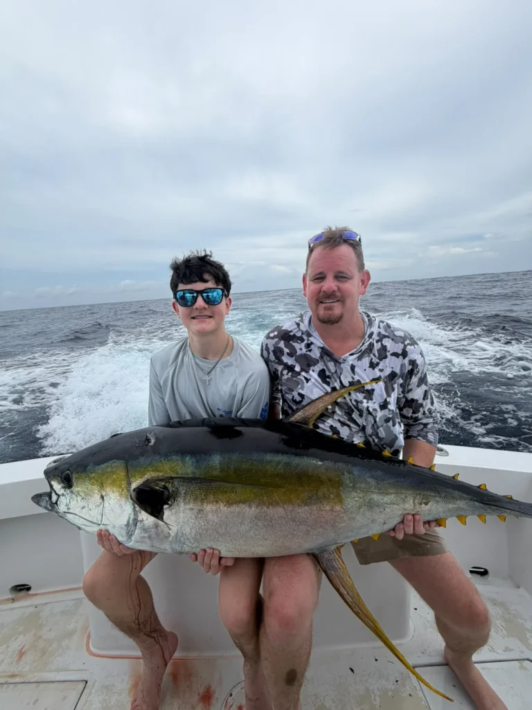 Family anglers holding a yellowfin tuna during a private Jaco fishing charter in late July 2026