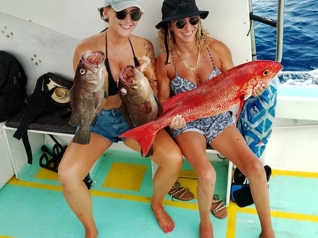 Two women displaying snapper and grouper catches during a private fishing trip near Jaco Costa Rica in August 2026