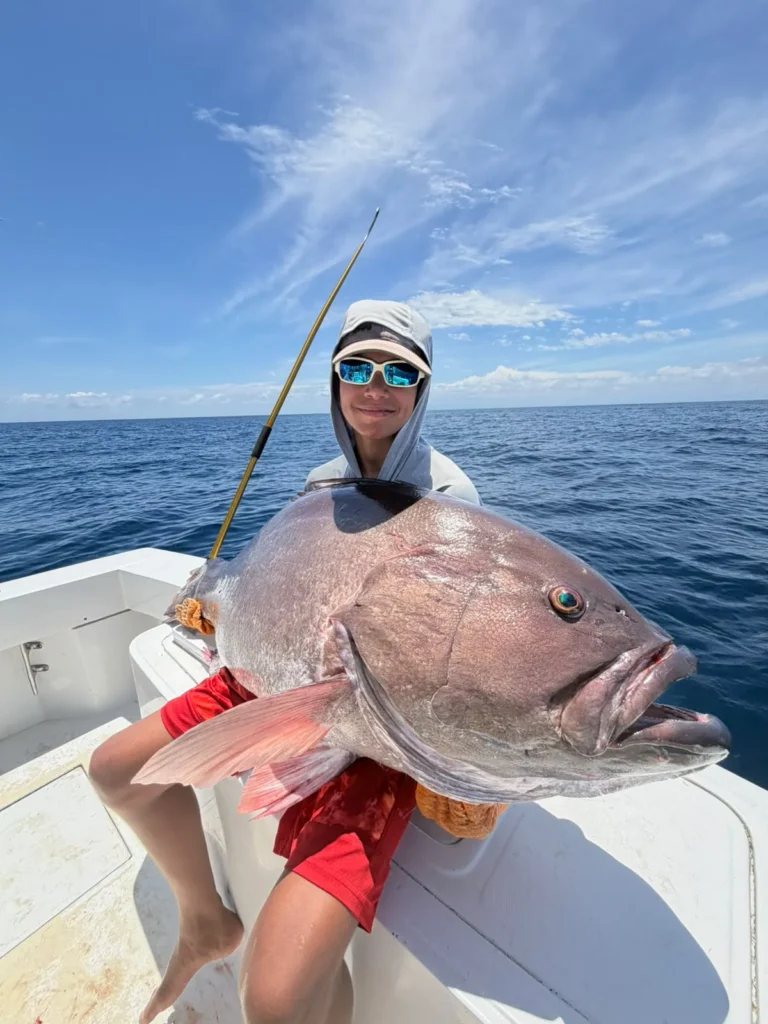Young angler holding a giant grouper during a bottom fishing trip from Jaco Costa Rica