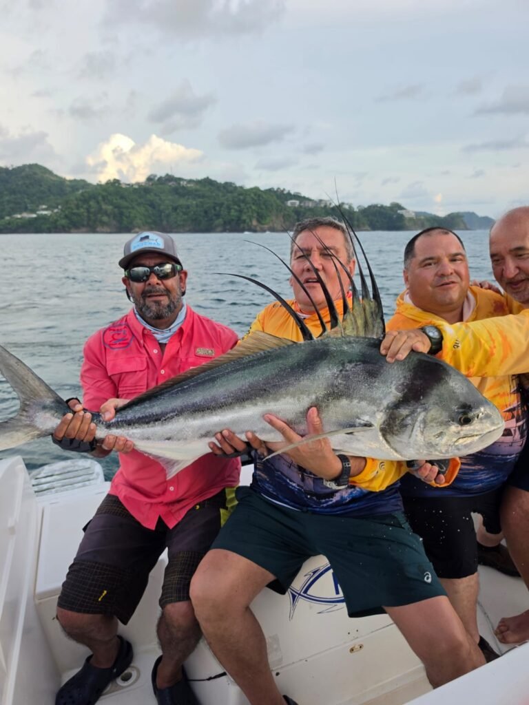 Anglers displaying a large roosterfish aboard a fishing boat